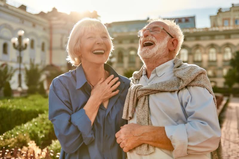 Couple de seniors riant dans leur jardin, sereins après une vente en viager occupé