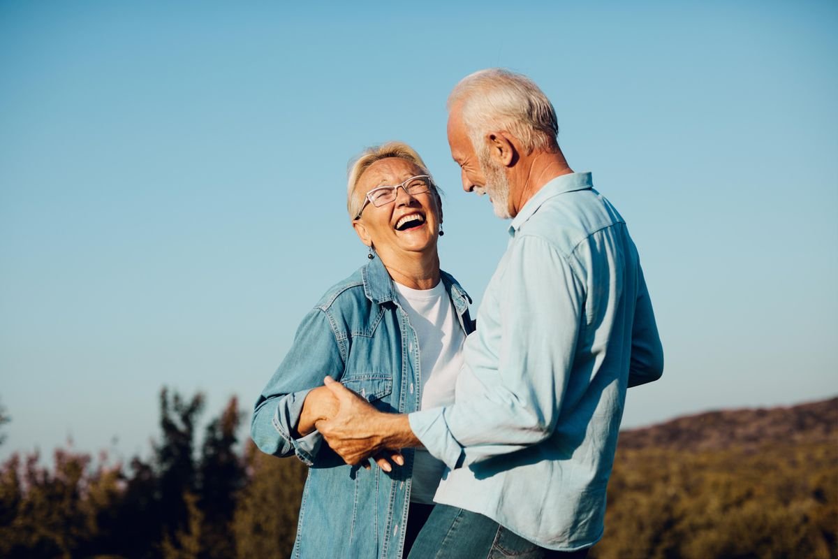 Couple de seniors souriants en plein air, le cadre verdoyant des coteaux de l’ouest lyonnais